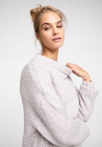 Pulover tricotat de culoare mov deschis, cu guler larg, mâneci lungi și un model texturat care include sclipiri subtile pe întreaga țesătură.
