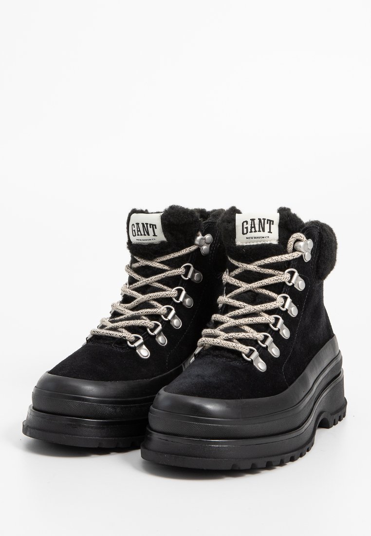 Czarne zamszowe buty trekkingowe z wyściełanym kołnierzem, srebrnymi detalami i teksturowanymi sznurowadłami. Gruba czarna gumowa podeszwa z wzorzystym bieżnikiem dla lepszej przyczepności.