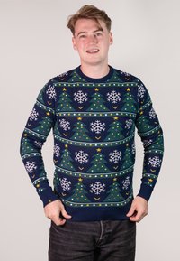 Knitted sweater featuring a dark blue background with green Christmas trees, white snowflakes, yellow stars, and colorful ornaments in a repeating pattern.