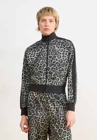 Giacca con zip in tessuto grigio e nero a fantasia leopardata, dotata di colletto alto, polsini aderenti e pannelli laterali a contrasto.