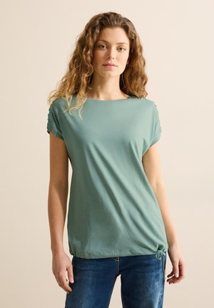 Lichtgroene shirt met korte mouwen gemaakt van zachte stof, met een ronde halslijn en geraffineerde accenten op de schouders. Koorddetail aan de zoom.