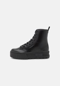 Botas de cuero negro hasta el tobillo con suela gruesa, con punta redonda, diseño con cordones y acentos texturizados en la plataforma.