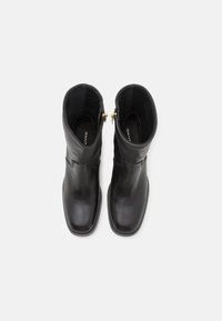 Black leather ankle boots with a smooth finish, rounded toe, and gold zipper accents at the ankles. Interior lined with soft material.