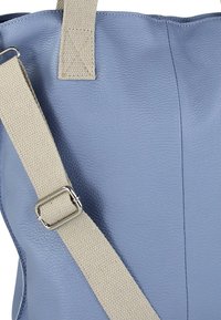 Blauwe leren draagtas met een gestructureerde afwerking, voorzien van een beige verstelbare band en zilverkleurige hardware. Strak ontwerp, zonder zichtbare patronen.