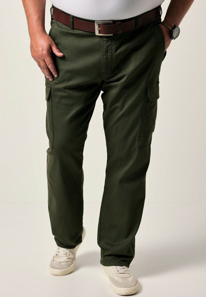 Pantalones cargo verde oliva con corte recto, cierre de botón y dos bolsillos laterales. Llevados con una camiseta blanca y zapatillas de color claro.