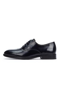 Shiny black leather Oxford dress shoe with closed lacing, cap toe, low heel, and small silver logo on the side.