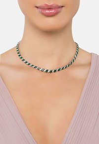 Emerald green and clear crystal choker necklace with marquise-cut stones set in silver-tone metal, worn on a smooth neckline.
