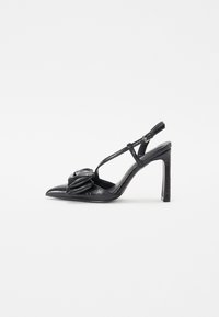 Chaussure noire à talons hauts avec un bout pointu, texture brillante, fines lanières et un détail plissé décoratif à l'avant.
