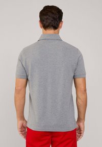 Polo grigio con colletto e maniche corte, caratterizzato da un tessuto testurizzato e un orlo dritto, abbinato a pantaloni corti rossi.