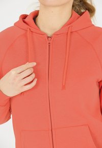 Koraal kleurige hoodie met rits aan de voorkant, verstelbare trekkoorden en voorzakken, gemaakt van zachte, gestructureerde stof.