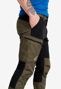 Cargo byxor i khaki och svart. Tillverkade av slitstarkt tyg med en zip-funktion på sidofickan, förstärkt sömnad och en smickrande passform.