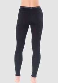 Black leggings made from stretchy material; features a wide waistband with logo, smooth texture, and fitted design, tapering at the ankles.