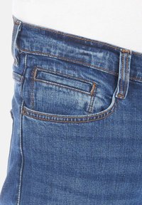 Jeans de denim azul, con un diseño clásico de cinco bolsillos, costuras visibles y un bolsillo trasero con un detalle decorativo en la costura.