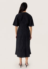 Black midi dress featuring eyelet patterns, short flutter sleeves, a round neckline, and a loose fit that falls above the ankles.