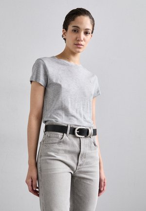 T-shirt cinza de algodão com mangas curtas, combinada com jeans rasgados de cintura alta em cinza claro e um cinto preto com uma fivela prateada.
