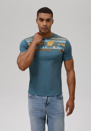 Camiseta de manga corta en color verde azulado con un gráfico de atardecer y palmera en tonos amarillos y azules. Fabricada en una tela ligera y texturizada.