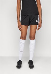 Mustad mustad püksid valgete külgede detailidega, millel on Kappa logo. Valged sääreavad sokid tekstuuri ja pehmendusega, koos mustade jooksujalatsitega.