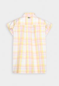 Chemise à manches courtes avec un motif à carreaux doux jaune, rose et blanc, vue de dos, avec un petit logo crocodile vert sous le col.