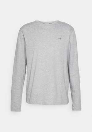 T-shirt en coton gris à manches longues avec un col rond et un petit logo brodé sur la poitrine. Texture douce et coupe décontractée.