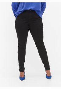 Jeans ajustados negros con una textura suave, con cierre de botón en la parte delantera y un corte slim. Combinados con zapatos de tacón azules.