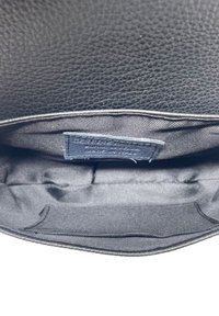 Interno di una borsa in pelle nera con una finitura testurizzata. Include un'etichetta in tessuto scuro che riporta la dicitura "Made in France". La fodera è liscia e scura.