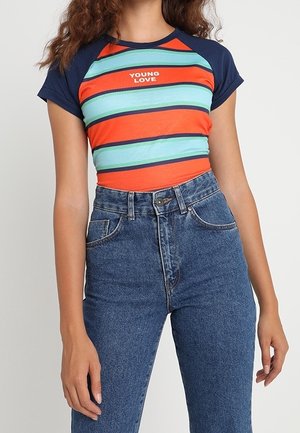 Gestreept shirt met korte mouwen met marineblauwe mouwen, rode en groene horizontale strepen, tekst "YOUNG LOVE", gecombineerd met een blauwe spijkerbroek met hoge taille.