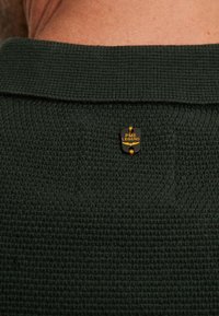 Dunkelgrünes, strukturiertes Strickpolohemd mit umgeschlagenem Kragen und einem schwarzen und goldenen PME Legend Logo-Tag auf der Rückseite.