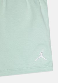 Svijetlozeleni pamučni shirt s bijelim izvezenim Jumpman logotipom u donjem desnom kutu, s glatkom teksturom i opuštenim krojem.