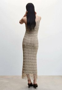 Robe midi en maille beige avec un motif à carreaux texturé, dotée d'un ourlet à franges et d'une silhouette ajustée. Vue de dos montrant des bretelles fines.