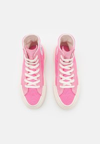 Różowe wysokie trampki wykonane z kanwy, z beżowymi sznurówkami i gumowymi podeszwami, o gładkiej teksturze i prostym wzornictwie.