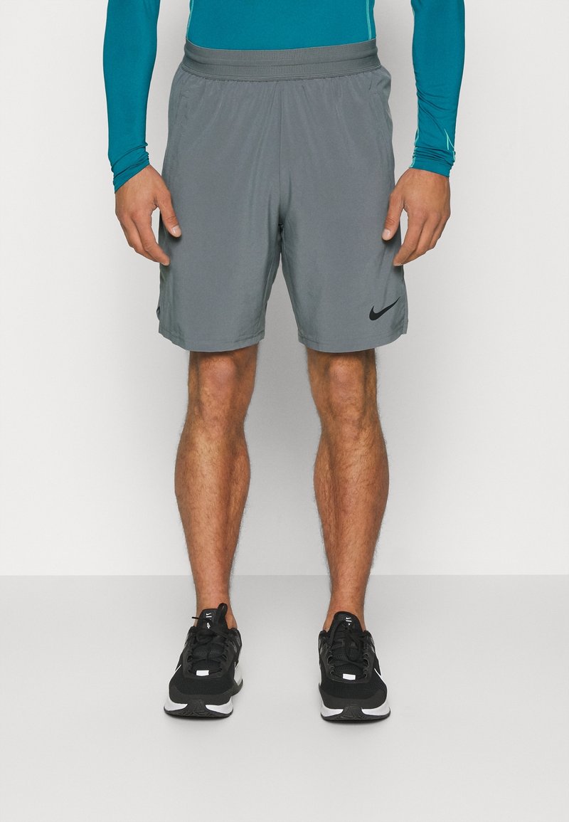 Shorts de sport gris avec une taille élastique, des poches latérales et un petit logo Nike noir sur l'ourlet gauche. Tissu léger, conçu pour le confort.