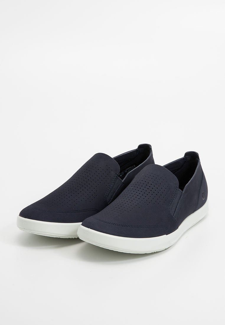 Granatowe slip-on'y z perforowaną cholewką, elastycznym fasonem i białą gumową podeszwą. Wyposażone w elastyczne panele boczne dla łatwego zakładania.