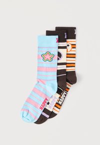 Τρία ζευγάρια κάλτσες με ρίγες και σχέδια με χαμογελαστά προσωπάκια, το καθένα με την ετικέτα "HAPPY" κοντά στην περιοχή των δακτύλων, σε παστέλ και σκούρα χρώματα.