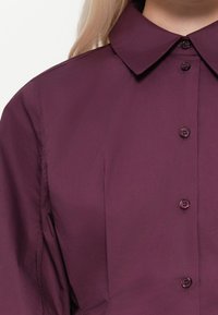 Bordeaux kleurige button-up shirt met een klassieke kraag, voorzien van een gladde textuur en een subtiele glans, vijf bijpassende knopen aan de voorkant.