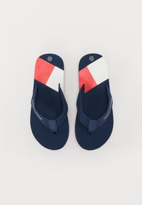 Marineblå flip-flops med en teksturert såle, med et rødt og hvitt geometrisk mønster på reimområdet og en liten logo på toppen.