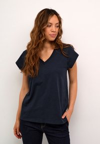 Tumed sinine V-kaelusega t-särk lühikeste varrukatega, valmistatud pehmest kangast, millel on mugav lõike ja sile, veidi tekstuuriga pind.