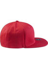 Red baseball cap with a flat brim, made of textured fabric. Features ventilation holes, a branded tag on the side, and a structured design.