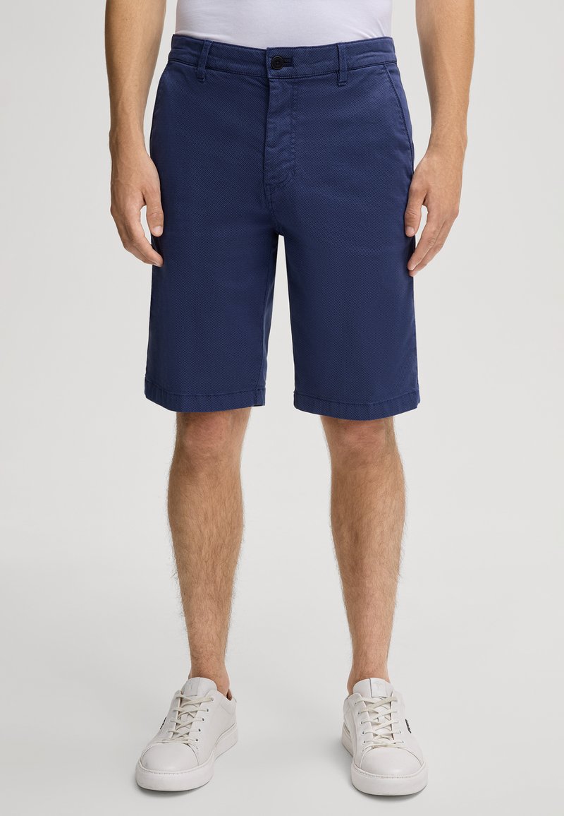 Pantaloni corti blu navy in un tessuto strutturato, con chiusura a bottone e passanti per cintura. Orli cuffati e tasche frontali e posteriori.
