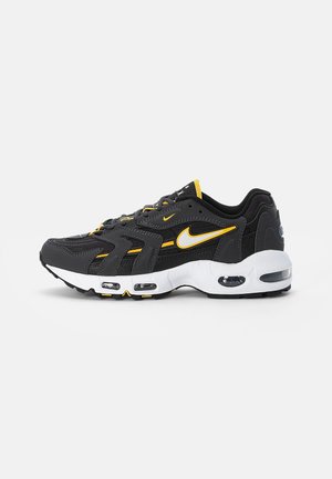 Baskets Nike Air Max noires et jaunes avec semelle blanche, amorti à air visible et logo Swoosh sur le côté, vues de l'extérieur.
