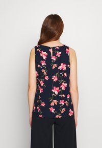 Haut sans manches bleu marine avec un motif floral rose et vert, doté d'une ouverture en forme de clé à l'arrière et d'une texture de tissu lisse.