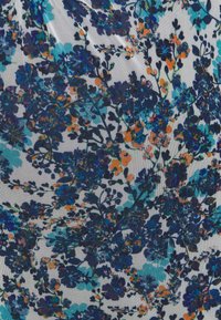Látka s hustým květinovým vzorem, který obsahuje tmavě modré, tyrkysové a oranžové květy na světlém pozadí s viditelnou texturou.