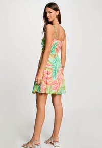 Abito con stampa floreale che presenta colori vivaci, spalline sottili, corpino arricciato e gonna a ruota. Abbinato a sandali con cinturini argentati.