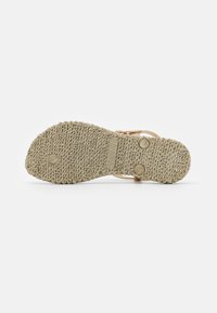 Sole di sandal beige chiaro con motivo testurizzato, caratterizzata da una forma sagomata, materiale in gomma e due evidenti bottoni metallici decorativi.