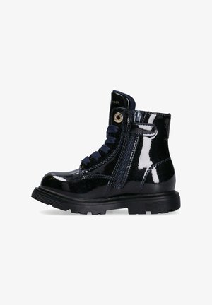 Stivale alla caviglia in pelle verniciata nera con suola spessa, presenta una cerniera laterale, lacci blu navy e un accento dorato vicino alla parte superiore.