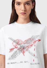 Λευκό βαμβακερό T-shirt με κόκκινη καρδιά, υπερθεματισμένο κείμενο και βέλος, με τη φράση "NO HEART... NO ART."