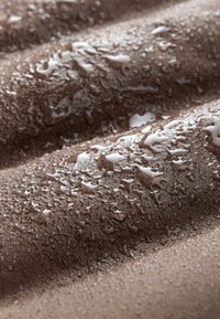 Pruun kangapind veetilkadega, millel on tekstuuriga välimus. Kangas tundub pehme ning nähtavad on niiskus ja läige.