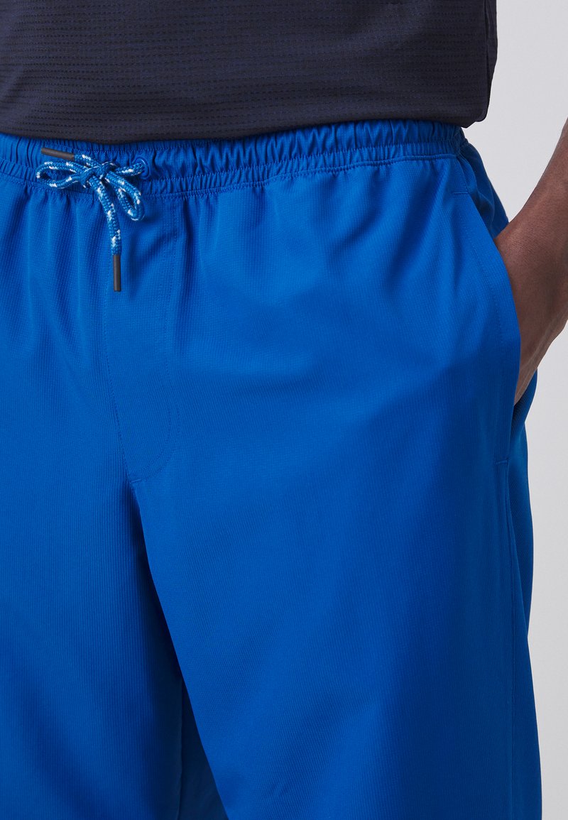 Pantalones cortos deportivos azules con una cinturilla elástica y cordón, bolsillos laterales y una textura de tela suave y ligera.