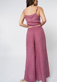 Completo in lino composto da due pezzi, con una parte superiore aderente senza maniche e pantaloni a gamba larga in un ricco colore mauve con una finitura testurizzata e cintura elasticizzata.