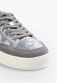 Szare sneakersy z teksturowanym zamszowym cholewką i metalicznymi srebrnymi akcentami. Wyposażone w okrągłe sznurowadła i masywną białą podeszwę.