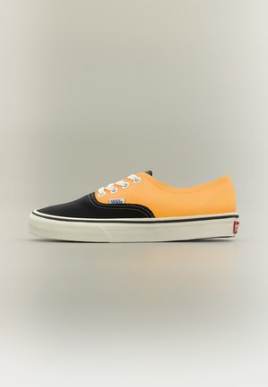 Low-Top Vans-Sneaker mit schwarzer Spitze und orangefarbener Ferse, weißen Schnürsenkeln und weißer Gummisohle mit schwarzem Streifen.